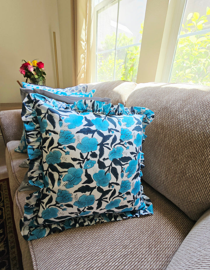Floral patterned pillow on a couch with a window in the background