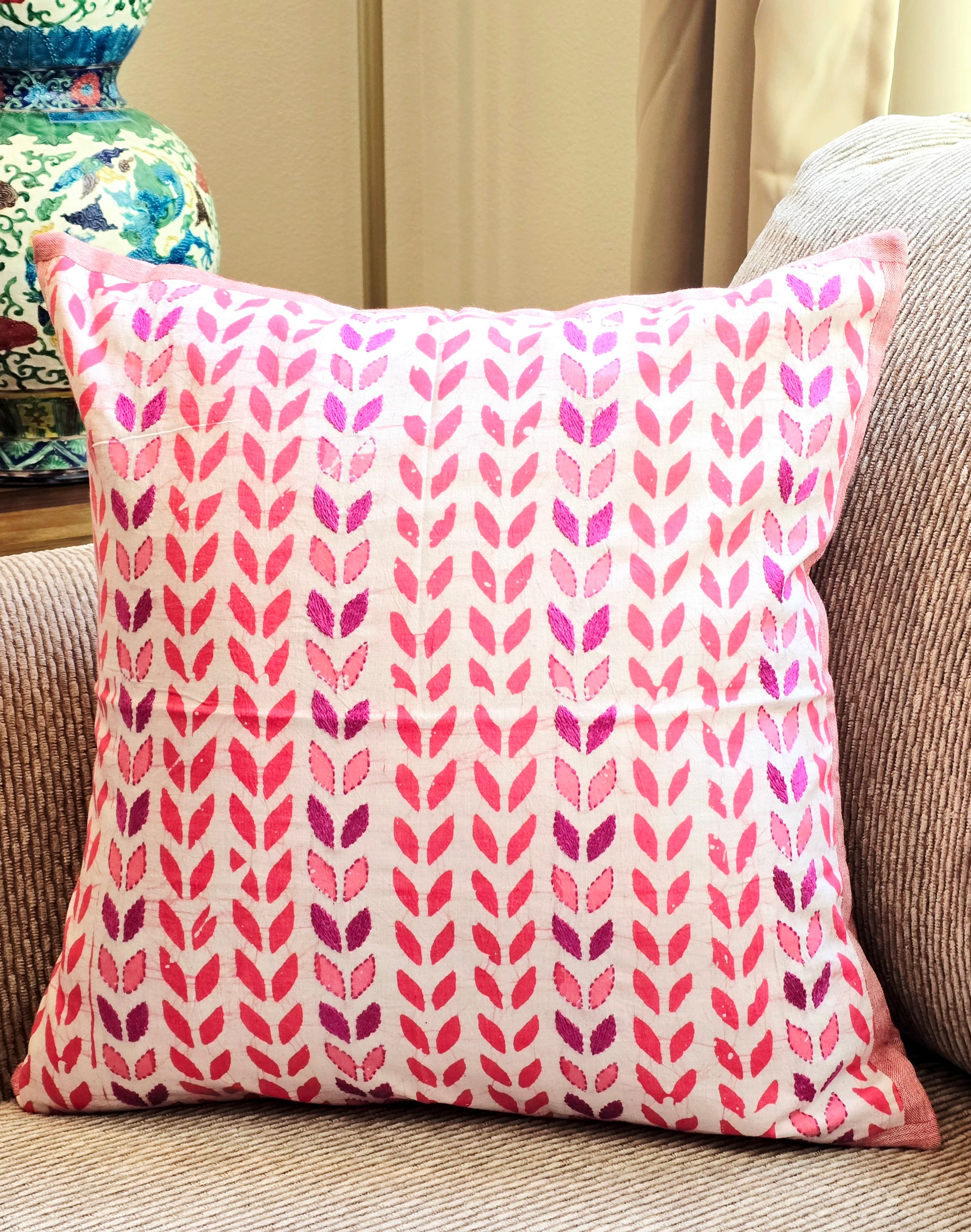Pink and purple patterned pillow on a beige couch