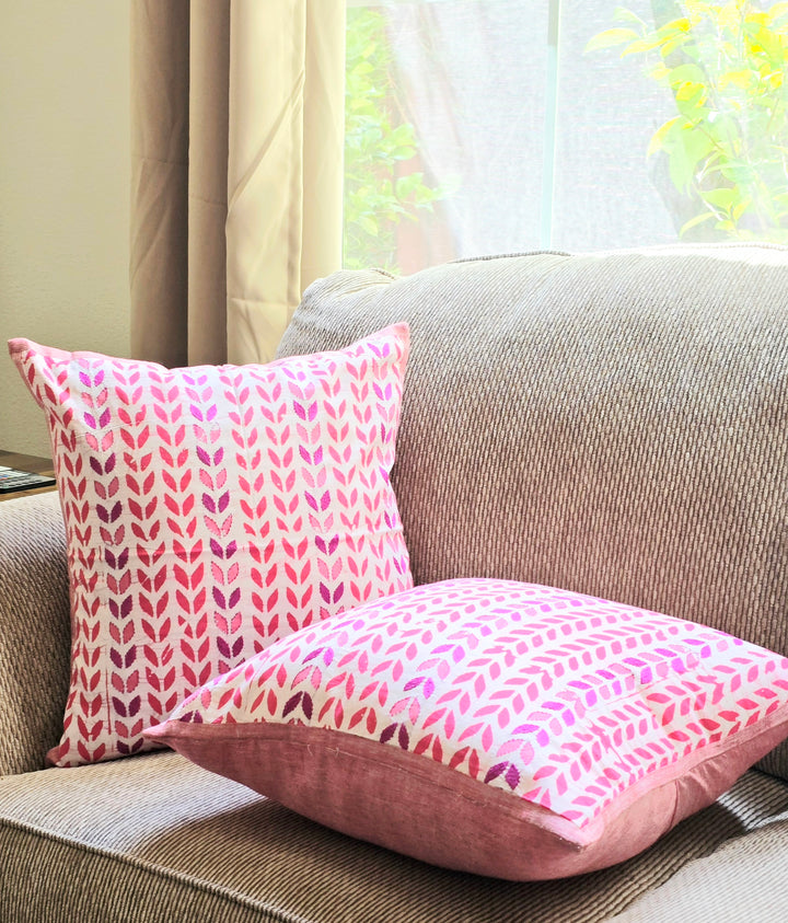 Pink patterned pillows on a beige sofa with a window in the background