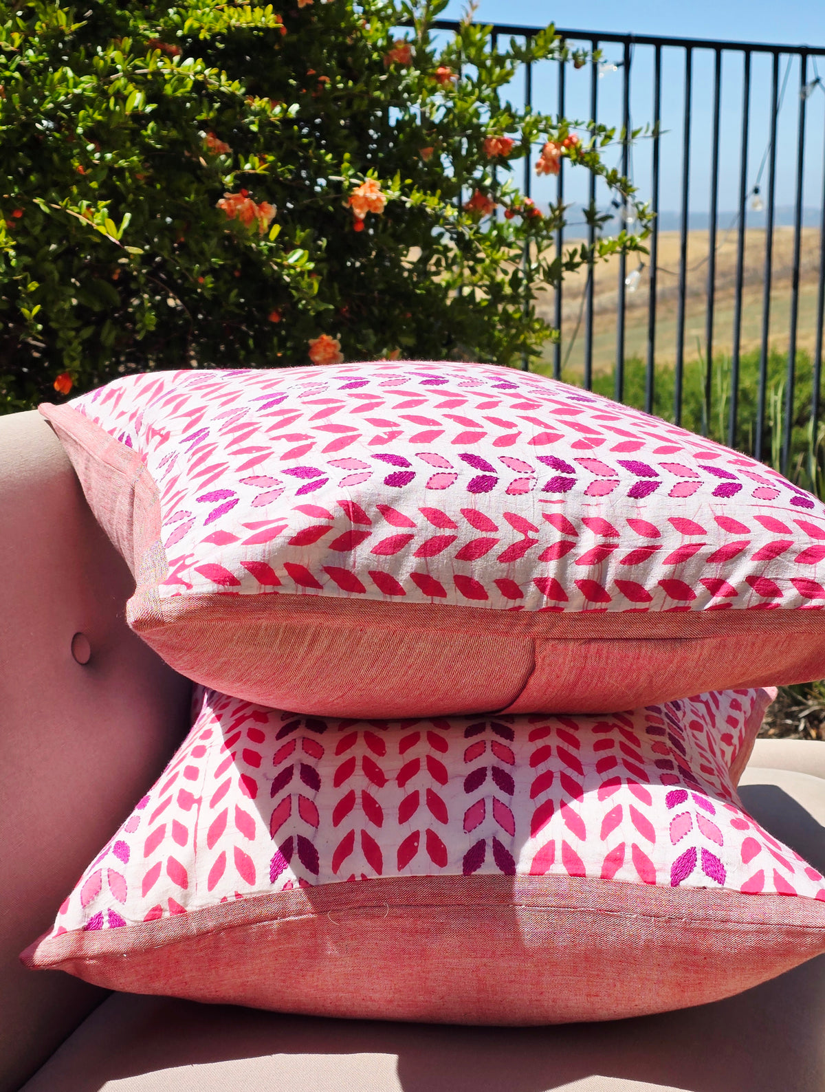 Pink patterned cushions on a sofa with a garden view in the background