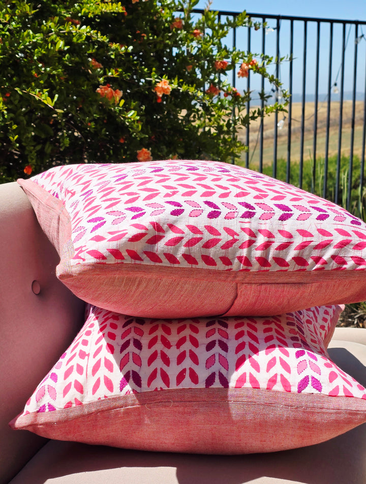 Pink patterned cushions on a sofa with a garden view in the background