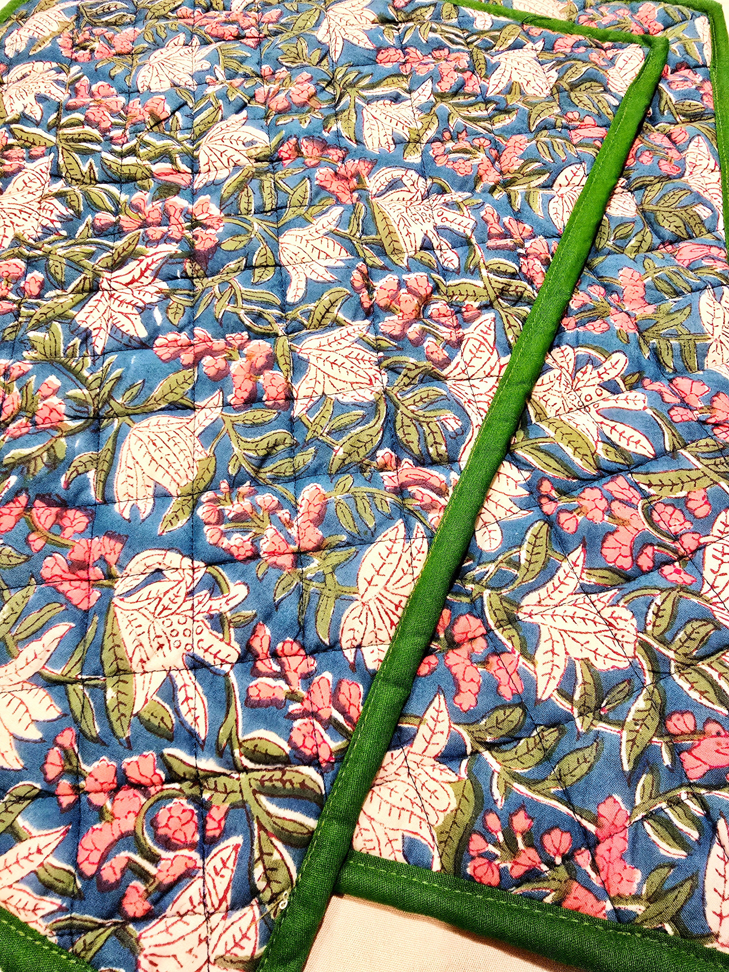 Close-up of floral blue cotton quilted placemat with soft stitched texture