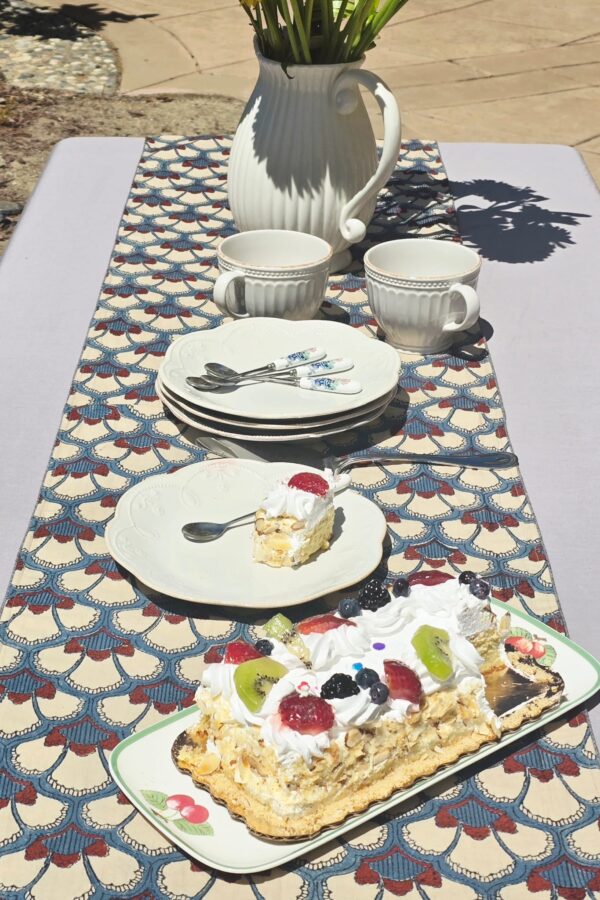 Hand block printed multicolor embroidered cotton table runner on outdoor dining table with floral centerpiece